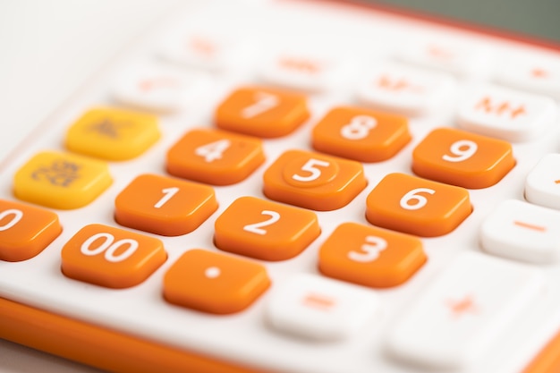 Pavé numérique sur la calculatrice de couleur orange pour la finance de compte au bureau.