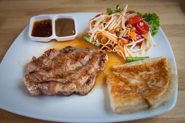 Pavé de porc avec roti et salade de papaye thaïlandaise.