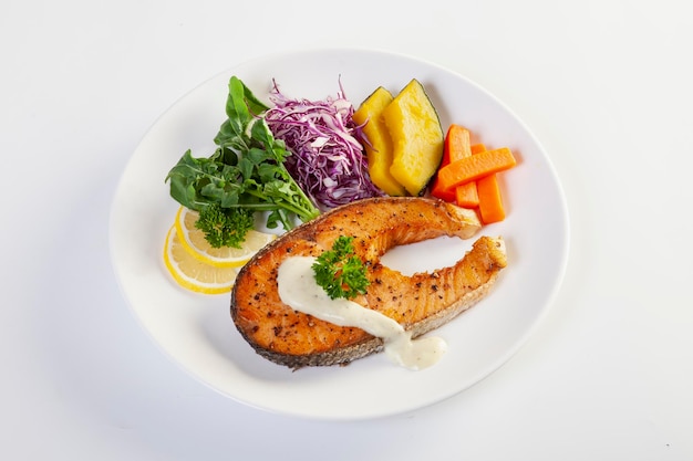 Pavé de saumon dans une assiette blanche sur fond blanc