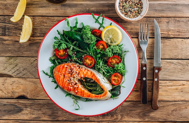 Pavé de saumon grillé et salade de légumes frais sur une table rustique en bois. Vue de dessus. Mise à plat