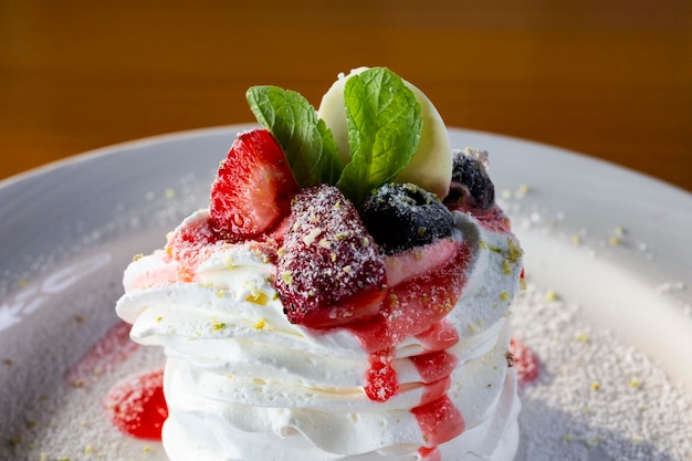 Pavlov dessert avec des blancs fouettés et des baies sur une assiette blanche