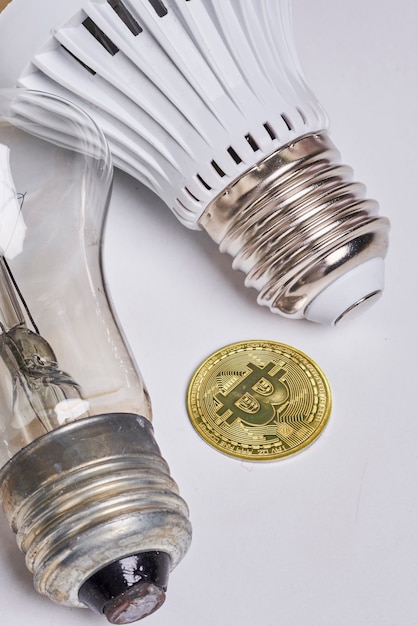 Payer l'électricité avec des ampoules électriques bitcoin crypto-monnaie et bitcoin doré sur blanc