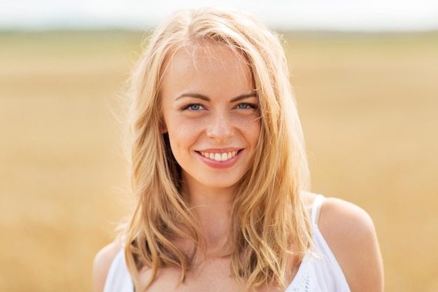 pays, nature, vacances d'été, vacances et concept de personnes - jeune femme souriante en blanc sur un champ de céréales