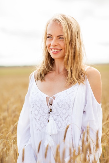 pays, nature, vacances d'été, vacances et concept de personnes - jeune femme souriante en robe blanche sur champ de céréales