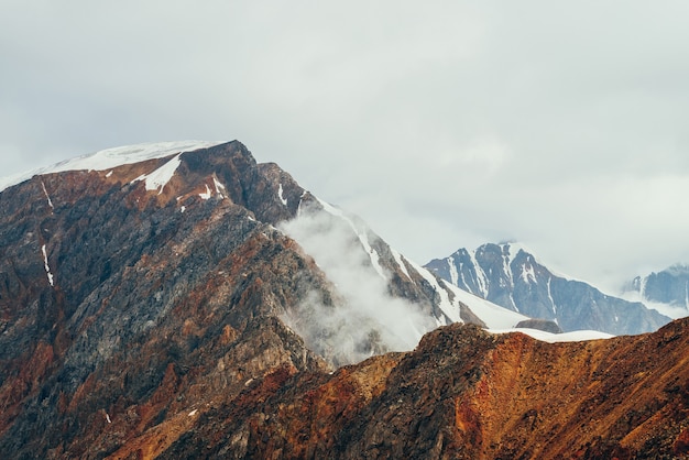 Paysage alpin atmosphérique avec des nuages bas sur les Rocheuses rouges à l'heure d'or