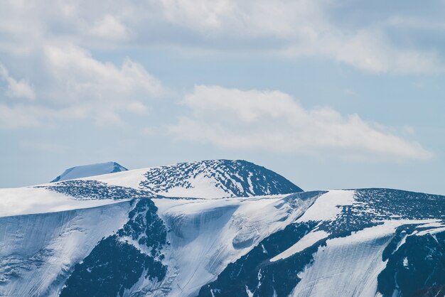 Paysage alpin minimaliste atmosphérique avec un glacier suspendu massif sur un sommet de montagne enneigé. Grand balcon sérac en bordure glaciaire. Ciel nuageux sur les montagnes enneigées. Paysages majestueux en haute altitude.