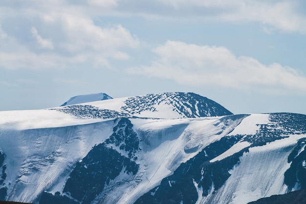 Paysage alpin minimaliste atmosphérique avec un glacier suspendu massif sur un sommet de montagne enneigé.