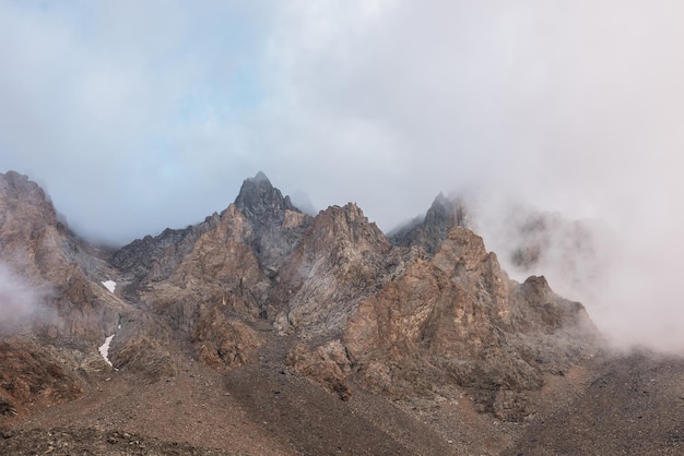 Paysage alpin pittoresque avec des montagnes rocheuses dans des nuages bas denses au soleil du matin Paysage de montagne coloré avec des rochers pointus parmi des nuages bas épais Vue imprenable sur les hautes Rocheuses dans une faible nébulosité