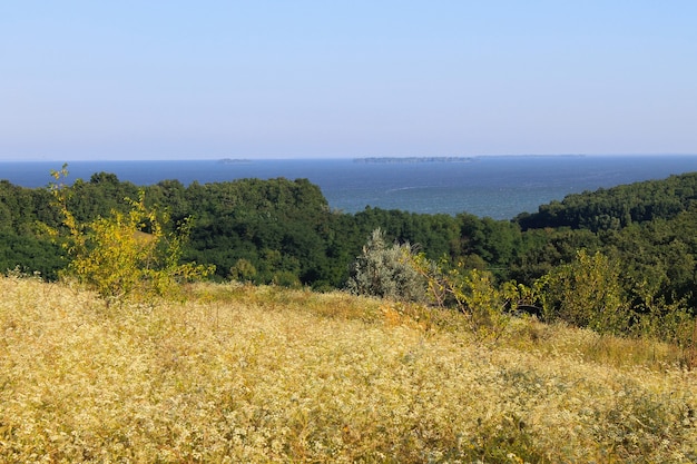 Paysage avec arbres, prairie, collines et rivière