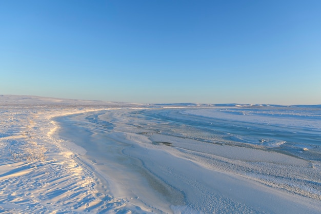 Paysage arctique en hiver. Petite rivière de glace dans la toundra. Coucher de soleil.