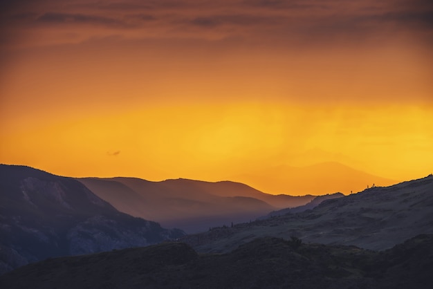 Photo paysage atmosphérique avec des silhouettes de montagnes et de collines avec des arbres sur fond de ciel d'aube orange. paysages naturels colorés avec coucher de soleil ou lever de soleil de couleur éclairante. paysage du coucher du soleil.