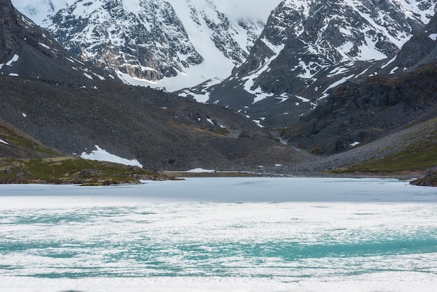 Paysage atmosphérique avec surface de lac gelée et hautes montagnes enneigées avec lumière et ombre Superbe paysage de montagne avec texture glacée de lac alpin gelé Lac de glace parmi de grandes montagnes enneigées