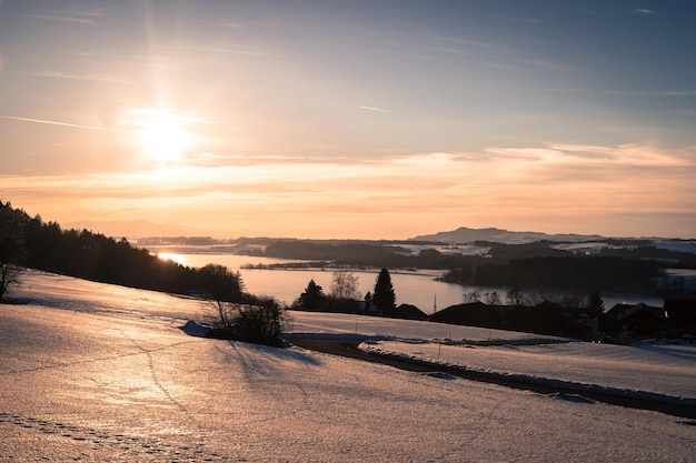 Paysage au coucher du soleil dans les champs enneigés du lac d'hiver et le coucher du soleil Wallersee Autriche