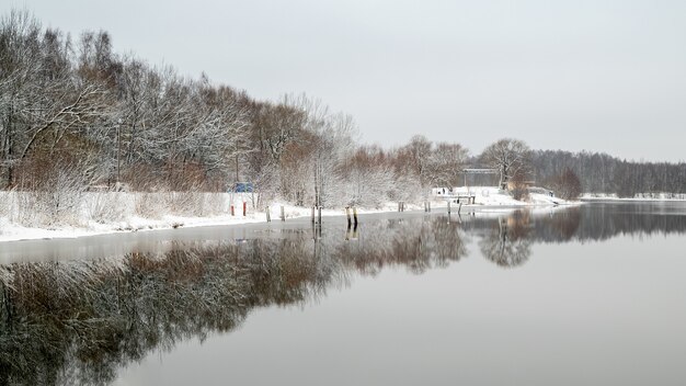 Paysage au début de l'hiver avec des arbres forestiers reflétée dans l'eau du lac