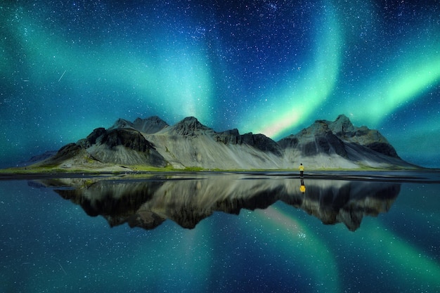 Paysage d'aurores boréales brillant sur la montagne Vestrahorn dans le village viking de la péninsule de Stokknes en Islande