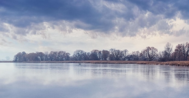 Paysage d'automne avec forêt d'arbres au bord du lac et ciel nuageux pittoresque par temps nuageux Réflexion du ciel avec des nuages dans l'eau de la rivière