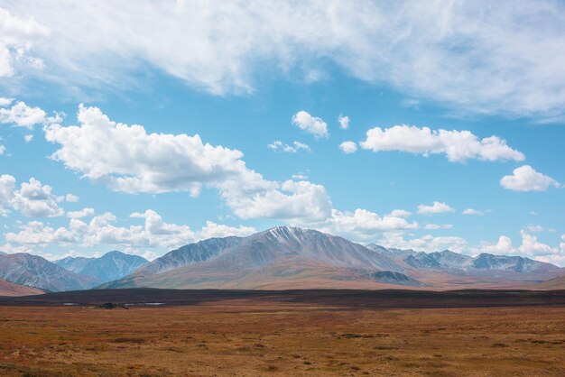 Paysage d'automne hétéroclite avec un plateau de haute montagne ensoleillé et un magnifique sommet de montagne sous un ciel nuageux spectaculaire Couleurs d'automne vives dans les montagnes Lumière du soleil et ombres des nuages dans un temps changeant