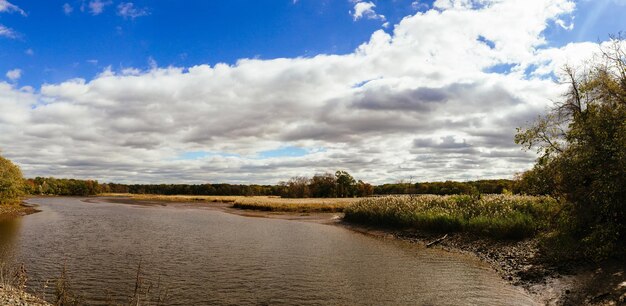 Paysage d'automne de rivière et d'arbres sans feuilles ciel bleu et nuages par une journée ensoleillée