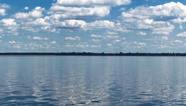 Le paysage balnéaire minimaliste et un beau ciel bleu plein de nuages au-dessus qui se reflètent dans la surface de l'eau.