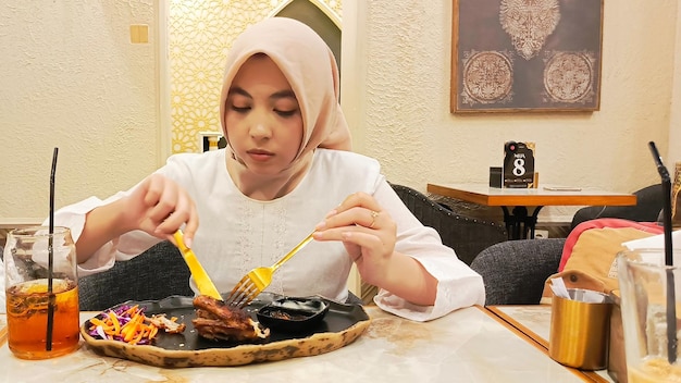 paysage d'une belle femme asiatique sincère tranchant du poulet rôti au four accompagné de pommes de terre khubu