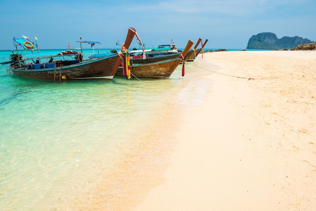 Paysage de la belle mer bleue et de la plage de sable blanc avec des bateaux traditionnels amarrés sur l'île tropicale