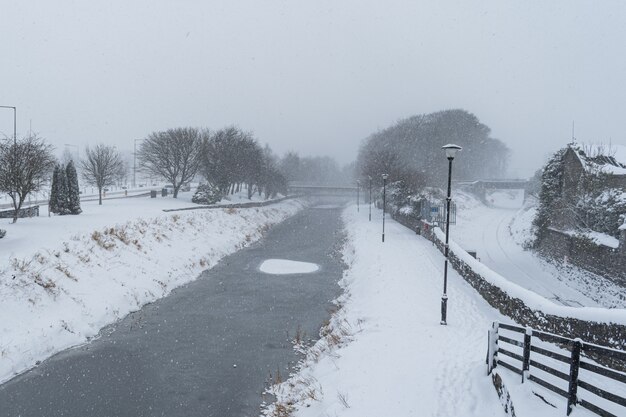 Paysage de canal gelé et de forêt au bord de l'eau dans une atmosphère hivernale enneigée.