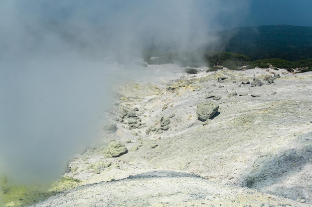 Le paysage d'un champ de fumerolles sur la pente d'un volcan est partiellement caché par des vapeurs denses