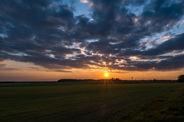 Paysage de champ vert avec ciel du soir bleu rouge rose avec de beaux nuages après le coucher du soleil