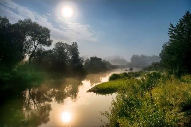 Paysage avec clair de lune la nuit sur la rivière. Brouillard au-dessus de l'eau et des arbres