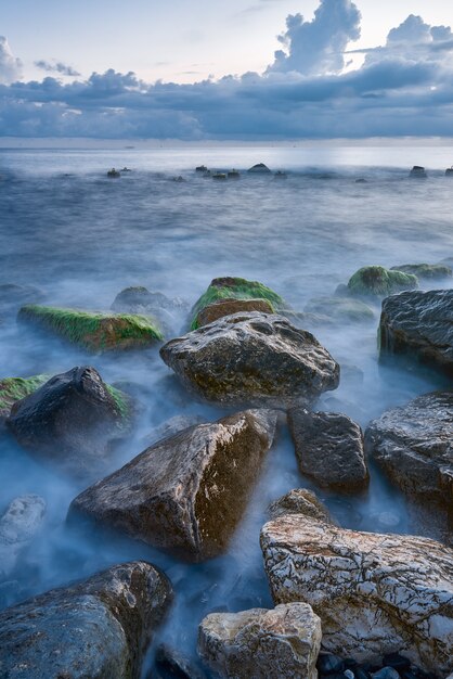 Paysage côtier avec une lumière chaude du soir lorsque les vagues se brisent sur des rochers recouverts d'algues