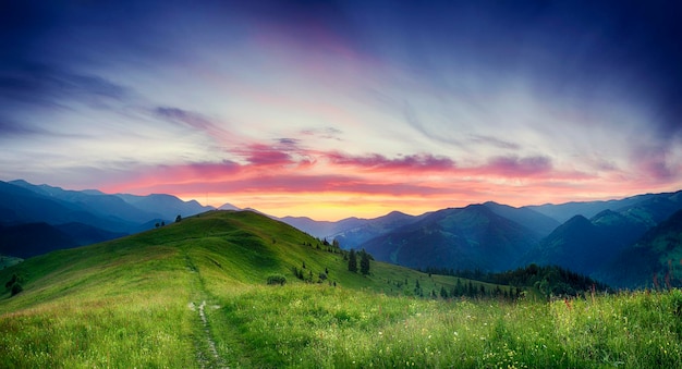 Paysage de coucher de soleil d'été des montagnes des Carpates avec un ciel dramatique et des montagnes bleues