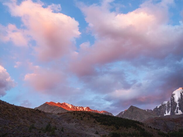 Paysage de coucher de soleil ou de lever de soleil vif avec des nuages bas dans la vallée de montagne en couleur éclairante Montagne rocheuse dans un ciel nuageux à l'aube