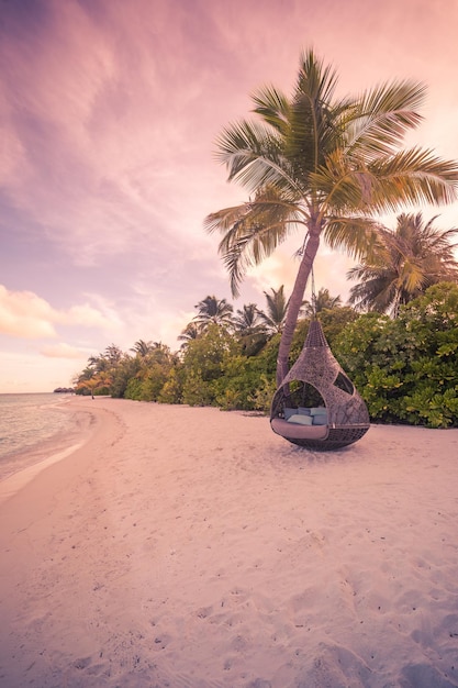 Paysage de coucher de soleil sur la plage tropicale, hamac oscillant sur la paume sous un ciel de rêve. Rivage romantique de sable de mer