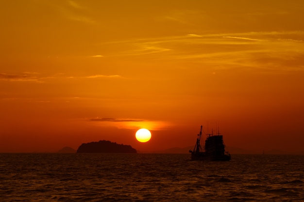 Paysage coucher de soleil Soleil entre l&#39;île et le bateau de pêche dans la mer.