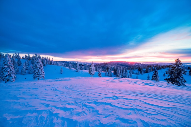 Photo paysage couvert de neige contre un ciel nuageux au coucher du soleil