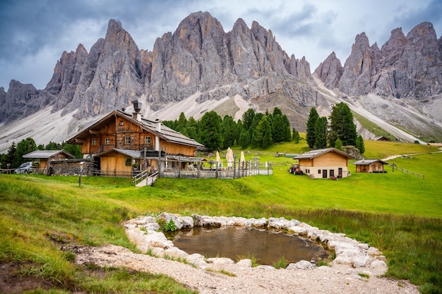 Paysage de Dolomite dans le parc naturel de Puez Odle, vue depuis le plateau alpin avec des maisons en bois et du vert