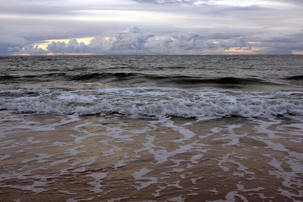 Photo paysage du coucher de soleil surplombant la mer le soir avec des nuages orageux au loin et des vagues de mer