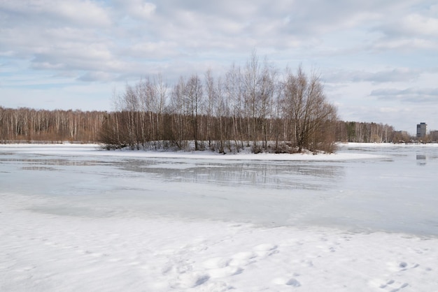 Paysage du lac au début du printemps avec une surface recouverte de neige fondante