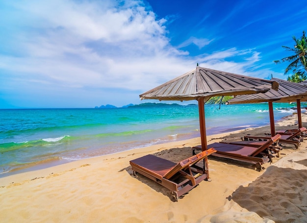 Paysage d'été d'une île tropicale Des branches de palmiers créent de l'ombre dans le sable Soleil éblouissant L'horizon est légèrement flou Transition de la plage de sable à l'eau turquoise