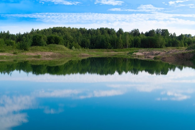 Paysage d'été de lac bleu pittoresque pour les vacances en plein air Ciel bleu et reflet des nuages dans l'eau claire de l'étang avec une forêt de verdure luxuriante en arrière-plan