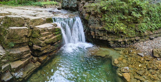 Paysage étonnant d'une belle cascade sur une rivière de montagne avec de l'eau mousseuse blanche tombant d'une falaise rocheuse dans la forêt tropicale d'été