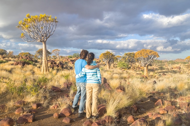 Photo paysage de forêt d'arbre carquois, couple de touristes regardant belle vue. kokerbooms en namibie, afrique du sud. nature africaine