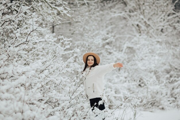 Paysage d'hiver avec des arbres enneigés. Fille heureuse debout près des arbres enneigés dans la forêt.