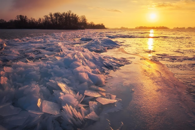Paysage d'hiver avec ciel ardent au coucher du soleil et côte de la mer glacée gelée