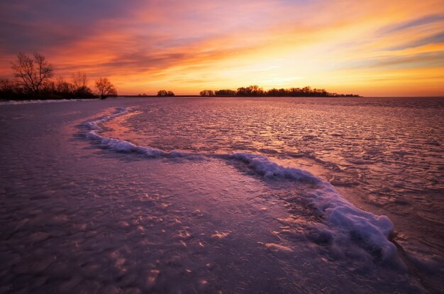 Paysage d'hiver avec ciel de feu au coucher du soleil et rivière gelée. Composition de la nature.