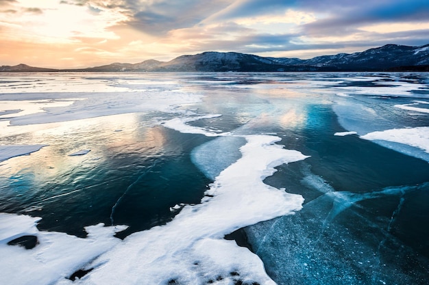 Paysage d'hiver fantastique avec lac gelé. Beau coucher de soleil avec ciel dramatique