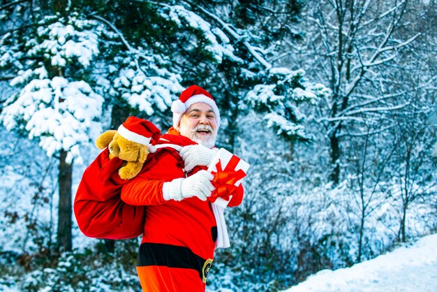 Paysage d'hiver de forêt et de neige avec le père noël père noël avec gros sac nouvel an noël con...