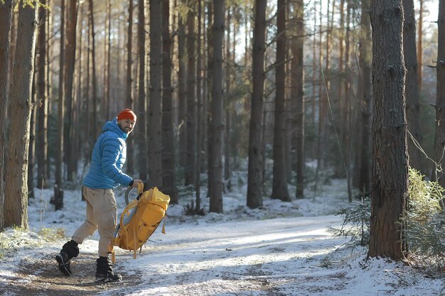 paysage d'hiver forêt sac à dos homme / voyageur en vêtements d'hiver modernes dans la forêt, voyageant dans les montagnes europe, suisse hiver