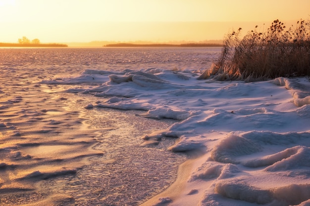 Paysage d'hiver avec lac gelé et ciel de feu au coucher du soleil. Composition de la nature.