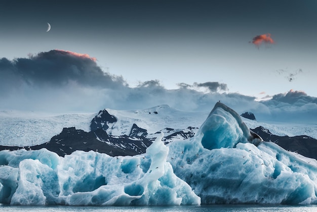 Paysage d'iceberg bleu flottant et la lune dans la lagune glaciaire de Jokulsarlon au crépuscule en été au parc national de Vatnajokull Islande